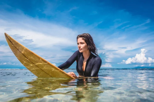 Junge sportlerin im neoprenanzug auf surfbrett im meer am strand von nusa dua, bali, indonesien — Stockfoto