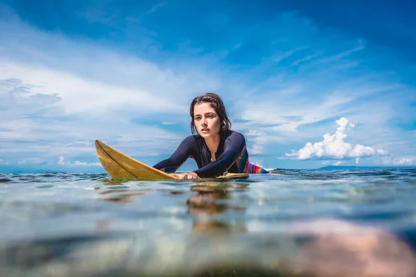 Ritratto di giovane sportiva in muta su tavola da surf in oceano a Nusa dua Beach, Bali, Indonesia — Foto stock