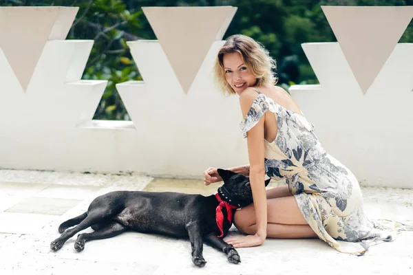 Mujer rubia en vestido descansando en la terraza junto con el perro - foto de stock