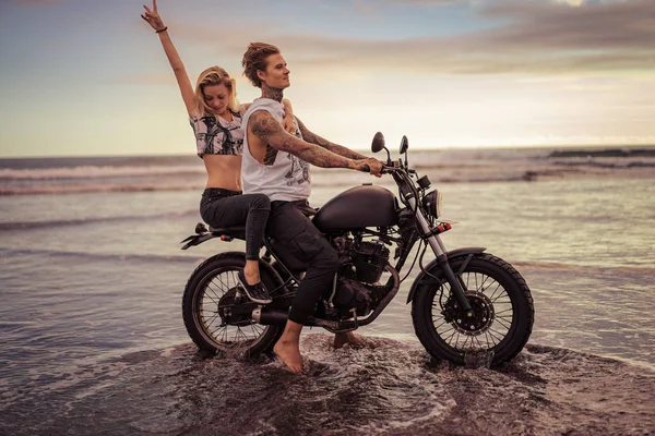 Novia mostrando la paz cantar durante la conducción de motocicletas en la playa del océano - foto de stock