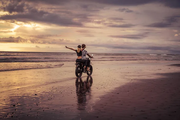 Rückansicht eines Motorradfahrerpaares am Sandstrand des Ozeans — Stockfoto