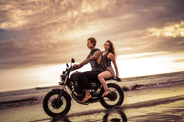 Couple riding motorcycle on ocean beach in morning — Stock Photo