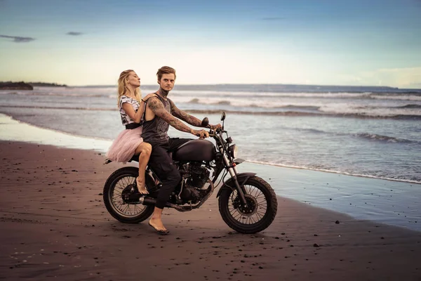 Couple sitting on motorbike on seashore during beautiful sunrise — Stock Photo