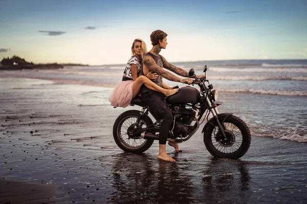 Vista lateral de la pareja abrazándose en moto en la playa del océano - foto de stock