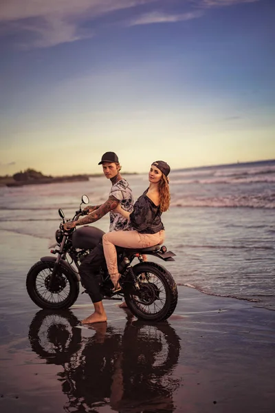 Vista lateral de la pareja a caballo motocicleta en la orilla del mar - foto de stock