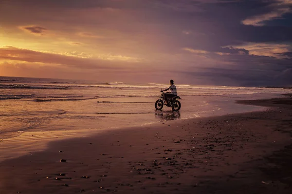 Homme à moto dans l'océan pendant le lever du soleil — Photo de stock