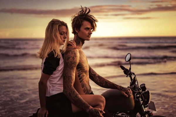 Vue latérale du couple assis sur la moto sur la plage de l'océan — Photo de stock