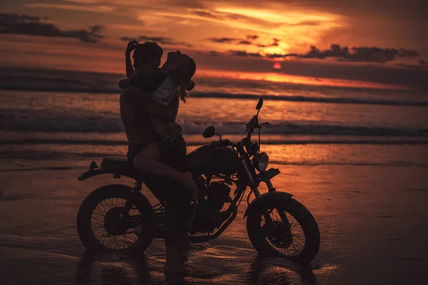 Sexy Paar umarmt sich auf Motorrad am Strand bei Sonnenuntergang — Stockfoto