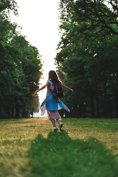 Вид сзади на молодую женщину с широкими руками, развлекающуюся в парке — стоковое фото