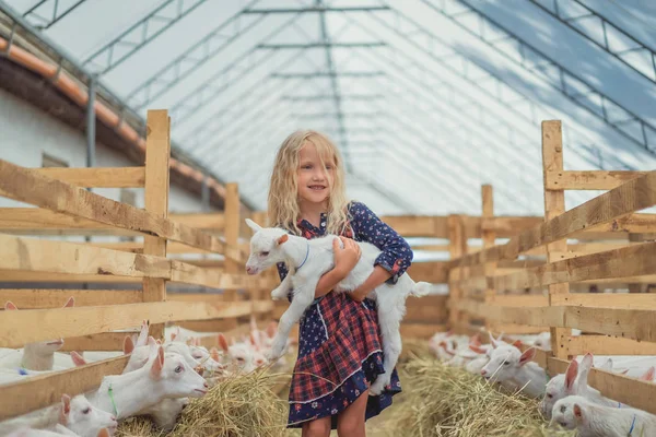 Smiling adorable kid holding goat at farm — Stock Photo