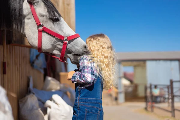 Kind umarmt Pferd in der Nähe von Stall auf Bauernhof — Stockfoto