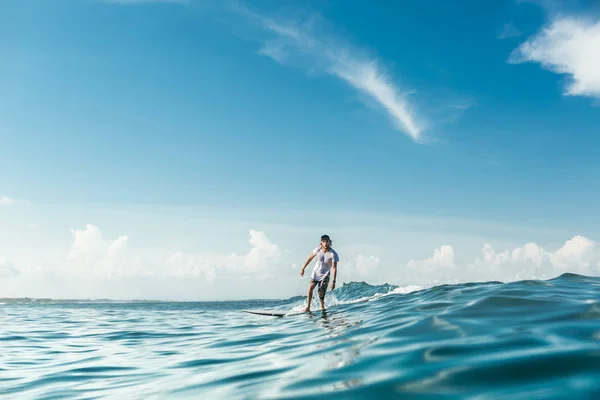 Vue lointaine de surfeurs masculins sur une planche de surf dans l'océan à Nusa Dua Beach, Bali, Indonésie — Photo de stock