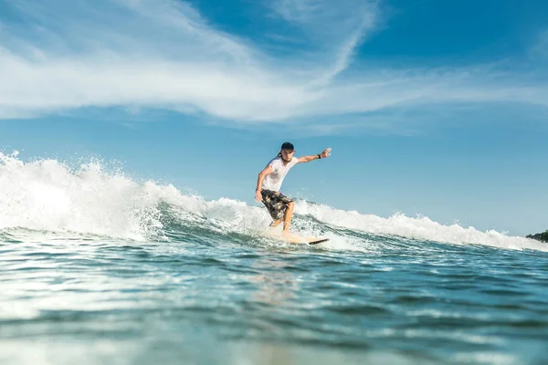 Joven surfista masculino montando olas en el océano en la playa de Nusa Dua, Bali, Indonesia - foto de stock