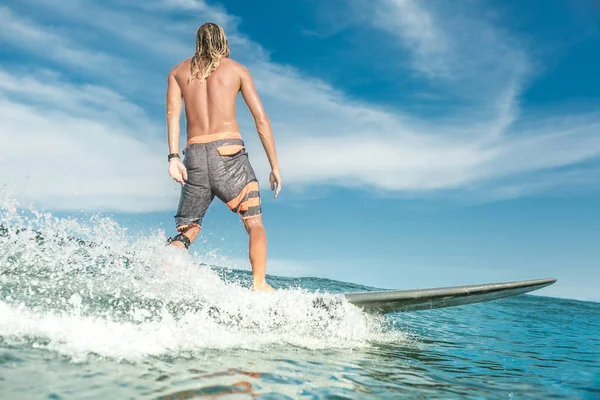 Rear view of shirtless male surfer riding in ocean at Nusa Dua Beach, Bali, Indonesia — Stock Photo