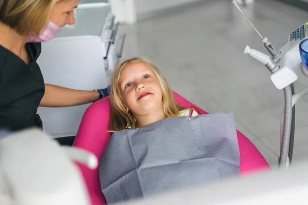 Vista parcial del dentista en máscara médica y niño sonriente en silla en el consultorio del dentista - foto de stock