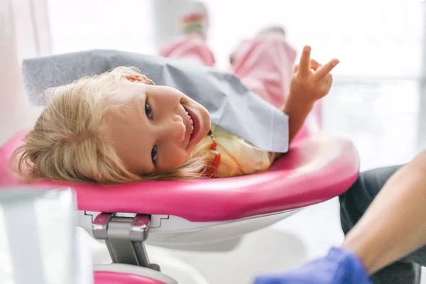 Портрет дитини, що показує знак миру в стоматологічному кабінеті — стокове фото