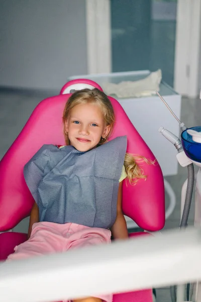 Портрет улыбающегося ребенка, смотрящего в камеру в кабинете стоматолога — стоковое фото