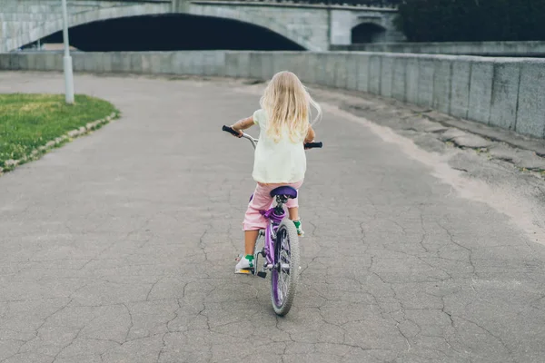 Vista posteriore del bambino biondo in bicicletta sulla strada — Foto stock