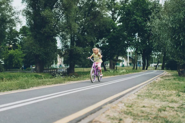 Little child riding bicycle on road in park on summer day — Stock Photo