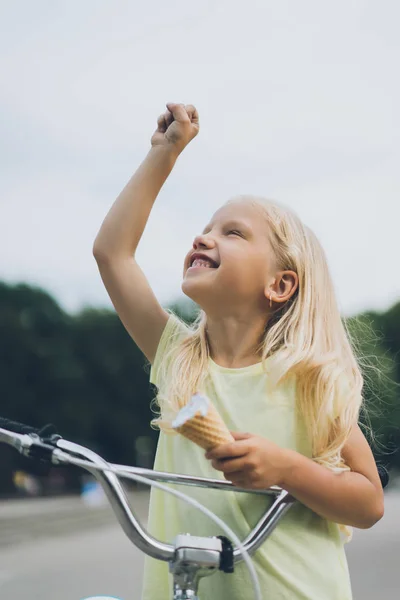 Portrait of smiling child with ice cream and bicycle gesturing on street — Stock Photo