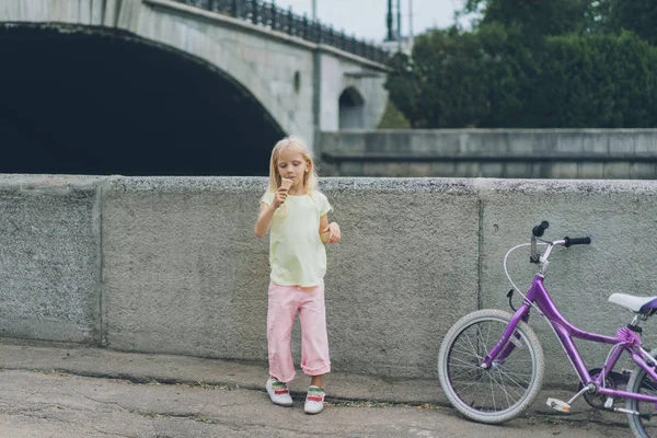 Piccolo bambino mangiare gelato in piedi vicino bicicletta sulla strada — Foto stock