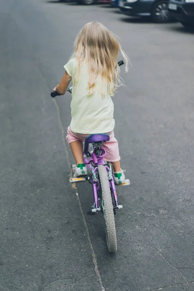 Back view of cute kid riding bicycle on street — Stock Photo