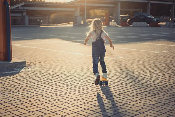 Visão traseira de criança montando no skate no estacionamento — Fotografia de Stock