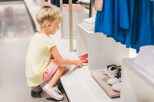 Seitenansicht des entzückenden kleinen Kindes, das Schuhe im Geschäft auswählt — Stockfoto