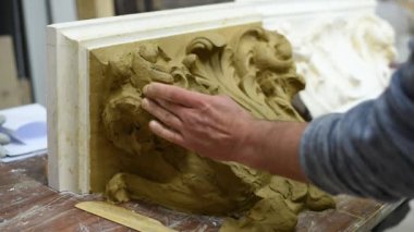 Heykeltıraş, Corinthian başkentinin kil modelini parşömenlerle ve restorasyon atölyesinde serpiştirilmiş akanthus yapraklarıyla oluşturur.