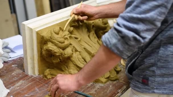 雕塑家在修复车间里用卷轴和展开的橡胶树叶来制作科林斯资本金的黏土模型 — 图库视频影像