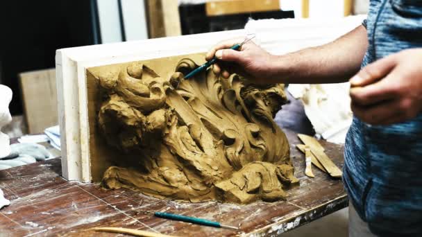 雕塑家在修复车间里用卷轴和展开的橡胶树叶来制作科林斯资本金的黏土模型 — 图库视频影像