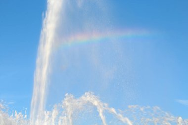 Gökyüzüne ve gökkuşağına karşı çağlayan çeşme