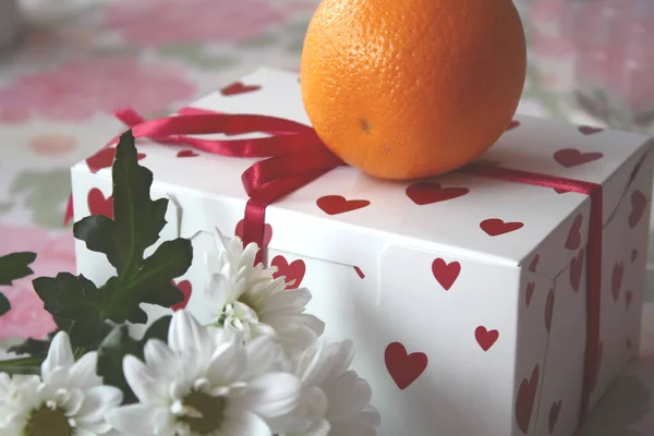 Kupa ve kurdeleli parlak turuncu bir hediye kutusu. Tatil hediyesi..