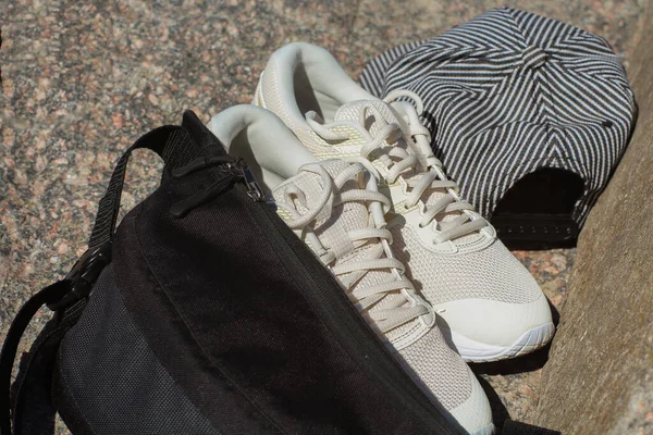 Siyah spor çantası, beyaz spor ayakkabılar ve taşlarda bir şapka. Spor yaptıktan sonra dinlen.