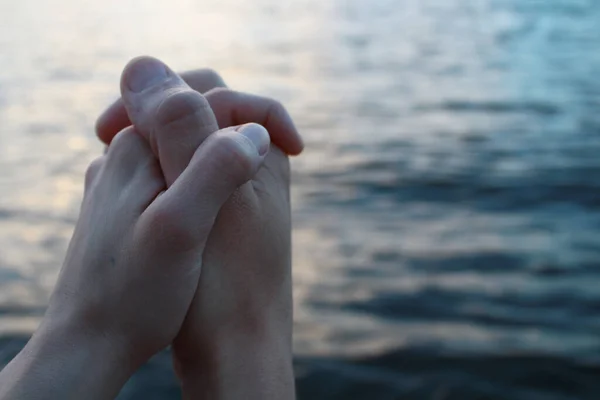 Aşıklar denizin arka planında el ele tutuşur.