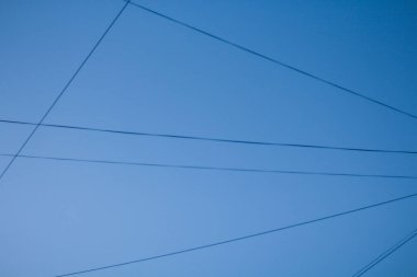 Mavi gökyüzü, elektrik kabloları ile sektörlere ayrılmış.