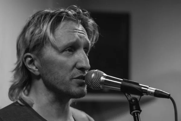 Genç adam stüdyoda mikrofona şarkı söylüyor.