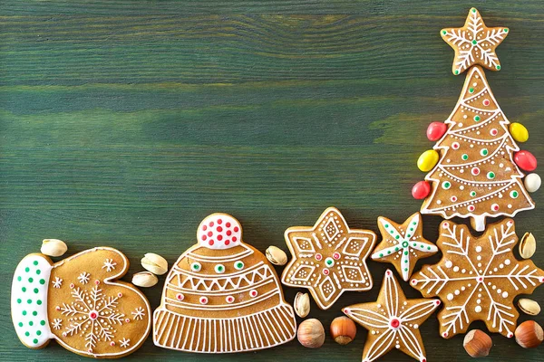 Noel zencefilli, farklı tatlılar, fındık ve süs eşyaları yeşil renk ahşap bir masa üzerinde yalan. Renk foto.