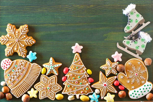 Noel zencefilli, farklı tatlılar, fındık ve süs eşyaları yeşil renk ahşap bir masa üzerinde yalan. Renk foto.