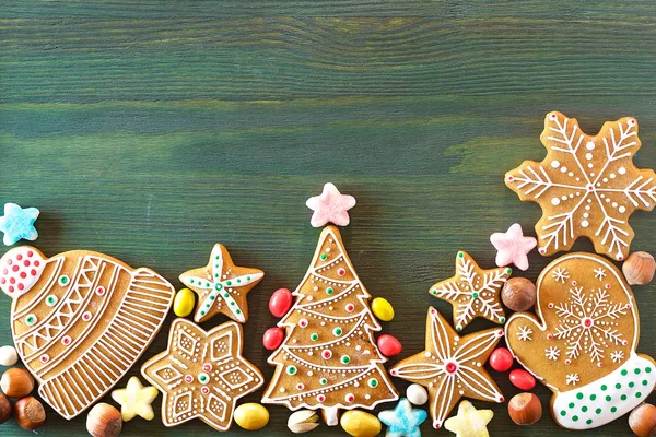 Noel zencefilli, farklı tatlılar, fındık ve süs eşyaları yeşil renk ahşap bir masa üzerinde yalan. Renk foto.