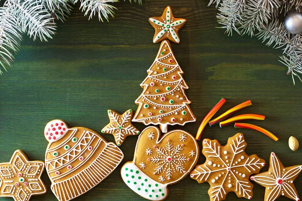 Christmas gingerbread, different sweets, nuts and ornaments lie on a wooden table of green color with spruce branches