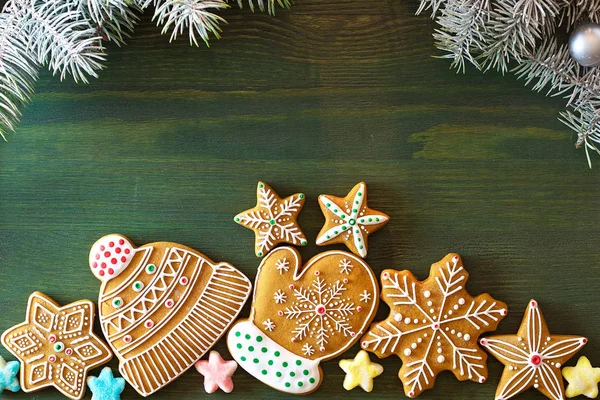 Christmas gingerbread, different sweets, nuts and ornaments lie on a wooden table of green color with spruce branches