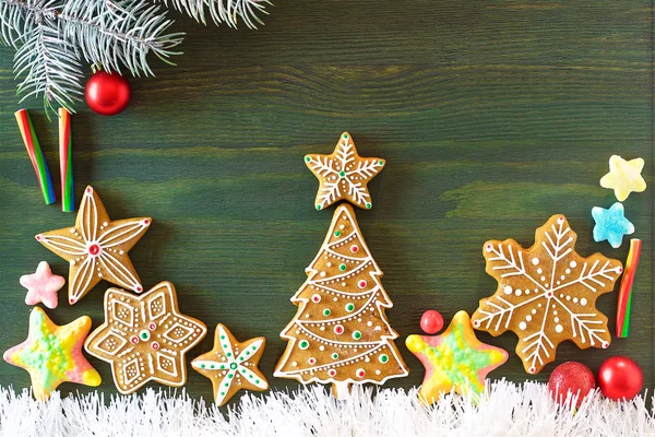 Christmas gingerbread, different sweets, nuts and ornaments lie on a wooden table of green color with spruce branches