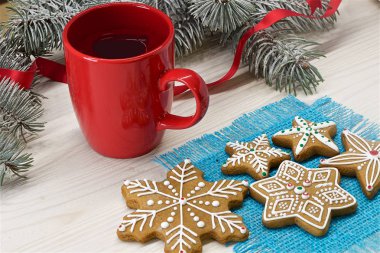 Bir fincan kahve, bir mum, zencefilli çörek ve tatlılar bly peçete ve ağaç dalları ile hafif ahşap arka plan üzerinde. Renkli fotoğraf