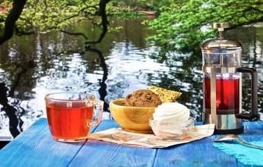 güzel manzaralar çeşitli arka planda mavi bir masada sıcak çay, Çaydanlık ve tatlılar