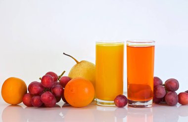 beyaz bir masada portakal ve üzüm suyu ve çeşitli meyveler gözlük vardır. Renkli fotoğraf.