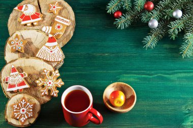yeşil ahşap arka planda üzerlerinde ağacın kesikleri vardır zencefilli çörek ve ladin dalları, hediyeler, çay ve dekorasyon bir fincan