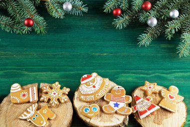 yeşil ahşap arka planda üzerlerinde ağacın kesikleri vardır zencefilli çörek ve ladin dalları vardır