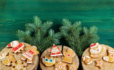 yeşil ahşap arka planda üzerlerinde ağacın kesikleri vardır zencefilli çörek ve ladin dalları vardır