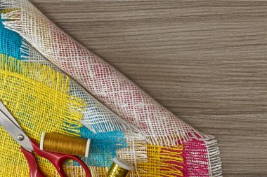 masaüzerinde çok renkli, pürüzlü pamuklu kumaş, iğne işi için alet ve iplikler